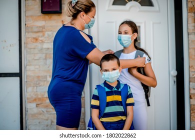 Boy And Girl Going Back To School,  Mother Giving Them Lunch Box. They Are Wearing A Protective Face Masks.