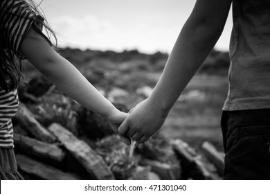 Boy and Girl holding hands in front of waste land