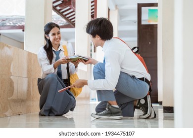 A Boy And A Girl In Indonesian High School Uniform Pick Up The Book Fell On The Floor Together