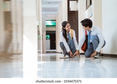 A Boy And A Girl In Indonesian High School Uniform Pick Up The Book Fell On The Floor Together