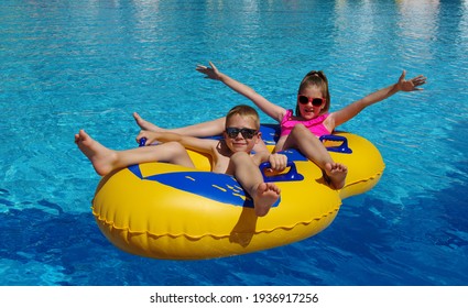 Boy and girl with inflatable ring in swimming pool .