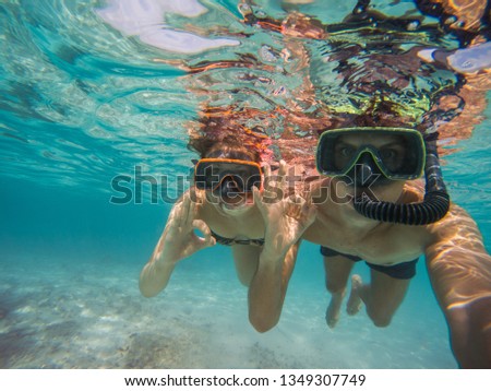 boy and girl in love with mask and flippers swim in clear blue water and taking a self portrait picture