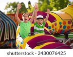 Boy and Girl on a thrilling roller coaster ride at an amusement park with arms raised and yelling with excitement. Summer fun concept photo