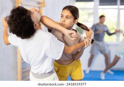 Boy and girl paired up and practice to aim stroke to neutralize opponent and repulse attack. Class self-defense training in presence of experienced instructor - Powered by Shutterstock