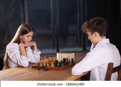 A boy and a girl play chess, teenagers play a board game, sports interest, schoolchildren are sitting at the table, learning to play chess.
 - Powered by Shutterstock