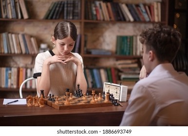 A boy and a girl play chess, teenagers play a board game, sports interest, schoolchildren are sitting at the table, learning to play chess.
 - Powered by Shutterstock