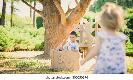 Boy and girl playing in a cardboard boat in the park. Eco concept