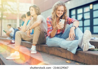 Boy And Girl Playing On Smartphones During Recess Between College Classes