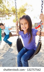 Boy And Girl Playing On Swing In Park