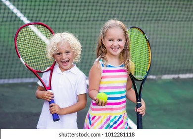 Boy and girl playing tennis on outdoor court. Kids with tennis racket and ball in sport club. Active exercise. Summer activities for children. Training for young kid. Child learning to play.