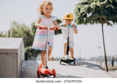Boy and a girl riding scooter together in park