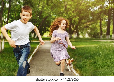 Boy and girl run in a park with a puppy jack russell terrier.