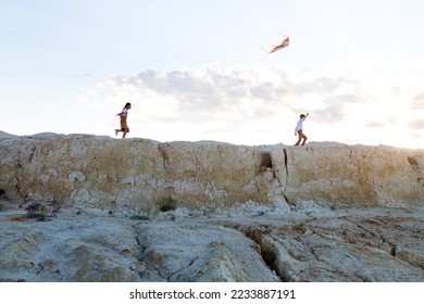 A boy and a girl running with kite on the mountainside. - Shutterstock ID 2233887191