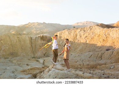 A boy and a girl running with a kite on the mountainside. - Shutterstock ID 2233887433