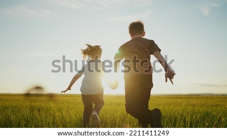 boy girl a running in the park. happy family kid dream holiday concept. children hold hands brother sister run across the field silhouette summer in the park. kids sun run