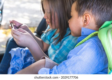 A Boy And A Girl, Siblings, Playing With A Cell Phone In The Back Seat Of A Car