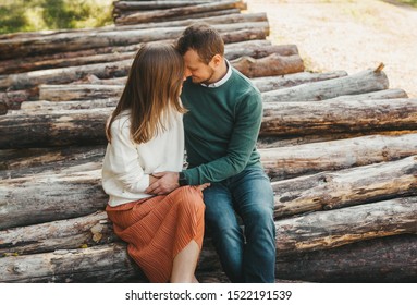 Boy and girl sitting on the stack of firewood and logs in the autumn forest. A walk of a couple in love in a beautiful colorful forest. Closeup portrait - Powered by Shutterstock