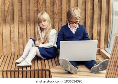 Boy And Girl Are Sitting Together. The Boy Looks At The Laptop And Does Not Pay Attention To The Beautiful Girl. Contemporary Problem Of Loneliness Together.