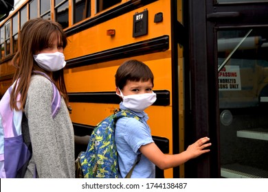 Boy and girl, students, children wearing face masks getting on school bus. For education, health, medical, environmental, and safety concepts regarding coronavirus, schools, reopening, and facemasks.