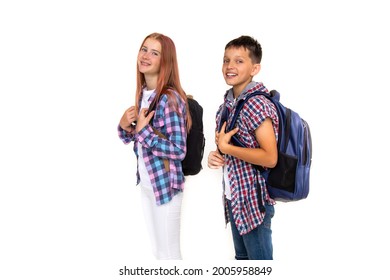 Boy And Girl Teenager 11 Years Old Schoolboy And Schoolgirl Looking At Camera On White Background With Backpacks And Smiling. Dressed In Plaid Shirt, White Shirt