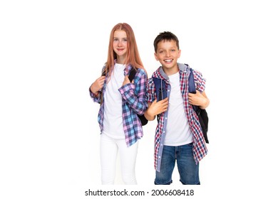 Boy and girl teenager 11 years old schoolboy and schoolgirl looking at camera on white background with backpack and smiling. Dressed in plaid shirt, white shirt