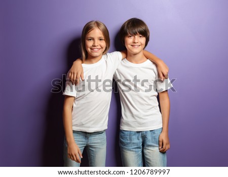 Boy and girl in t-shirts hugging each other on color background