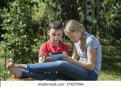 Boy and girl of twelve years in nature with iPads.