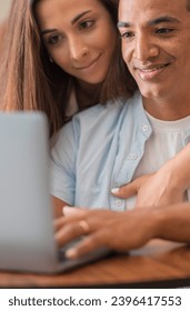 Boy and girl using together a laptop at home sitting and enjoying the web. Young couple interracial people working on computer and smiling. People and technology. Man and woman use notebook online - Shutterstock ID 2396417553