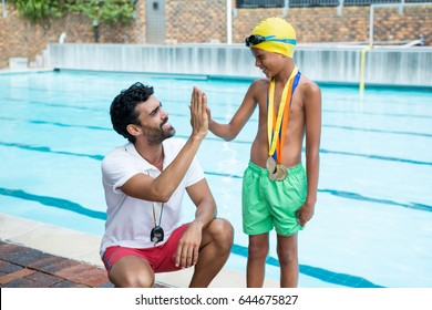 Boy giving high five to coach near poolside at the leisure center - Powered by Shutterstock