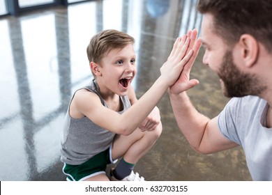 Boy Giving High Five To His Adult Friend At Fitness Center