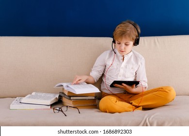 Boy in glasses on self isolation using digital tablet for his homework, for searching information on internet while school of during covid-19 lock down, social distance, learning online education