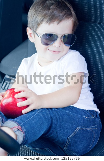 Boy with\
glasses and red apple sitting in\
car
