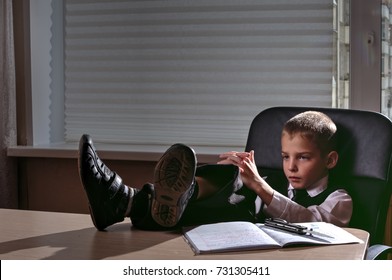 Boy As The Godfather Of The Mafia Sits Throwing His Feet On A Table In Darkened Office. On The Table A Folding Knife. Focus On The Hands.