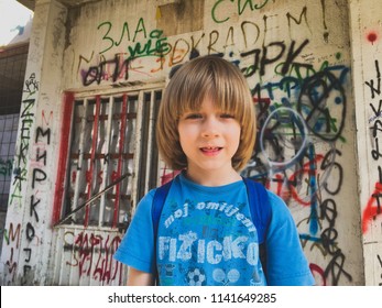 Boy goes to school with backpack in front of the graffiti wall