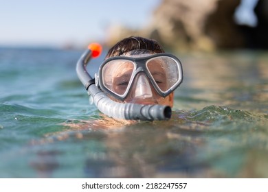 Boy with goggles and pipe before diving at rocky seashore portrait