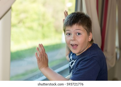 Boy grimaces standing at the train window