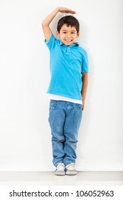 Boy growing tall and measuring himself on the wall
