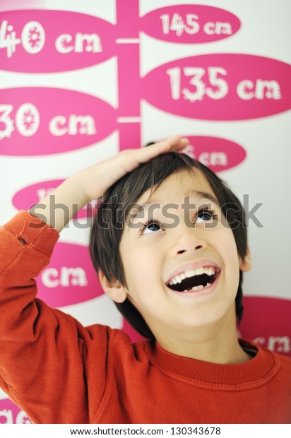 Boy\
growing tall and measuring his height on the\
wall