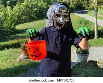 Boy In Halloween Mask With Orange Bucket And Scary Beast Gloves. Trick Or Treating