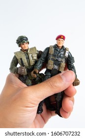 Boy Hand Holding Mini Toy Soldiers On White Background.