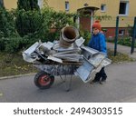 boy in a hat carrying metal for change, dysfunctional family, poverty, child labor, metal, secondary raw materials, hat with a pompom, poor family, boy with a wheelbarrow