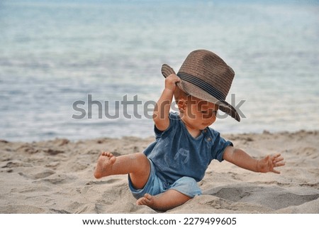 boy with a hat on the beach, falling down