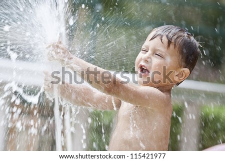 boy having fun with fountain shot during summer time