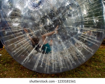 Boy Having Fun Inside A Giant Plastic Hamster Ball On The Lawn.