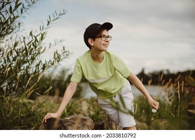 boy having fun on rocks while climbing on hard stone shore and discovering new things