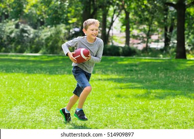 Boy Having Fun Running With Rugby Ball In The Park