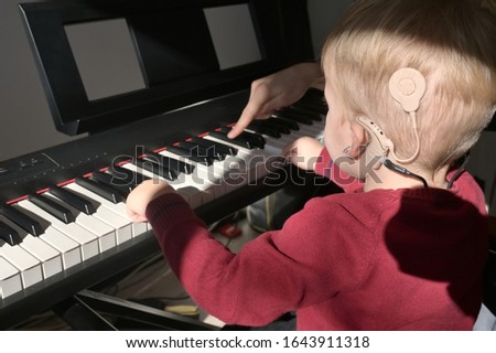 A Boy With A Hearing Aids And Cochlear Implants Playing Piano