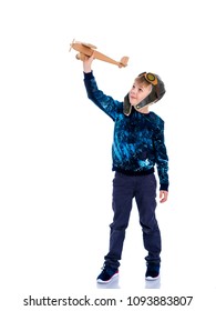 The boy in the helmet of the pilot plays with a toy wooden plane. He dreams of becoming a pilot. Concept of happy childhood, child in the family.Isolated on white background.