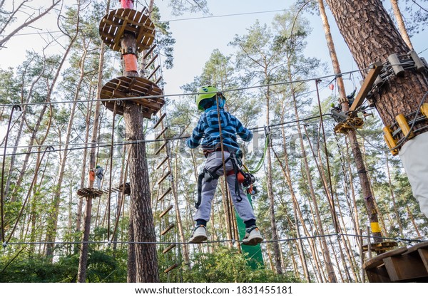 A boy in a helmet walks on a rope in the\
park on a sunny summer day at the playground in the forest. Active\
healthy leisure concept with children\
..