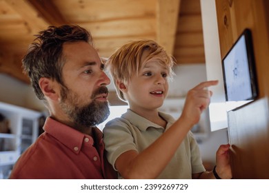 Boy helping father to adjust, lower heating temperature on thermostat. Concept of sustainable, efficient, and smart technology in home heating and thermostats. - Powered by Shutterstock